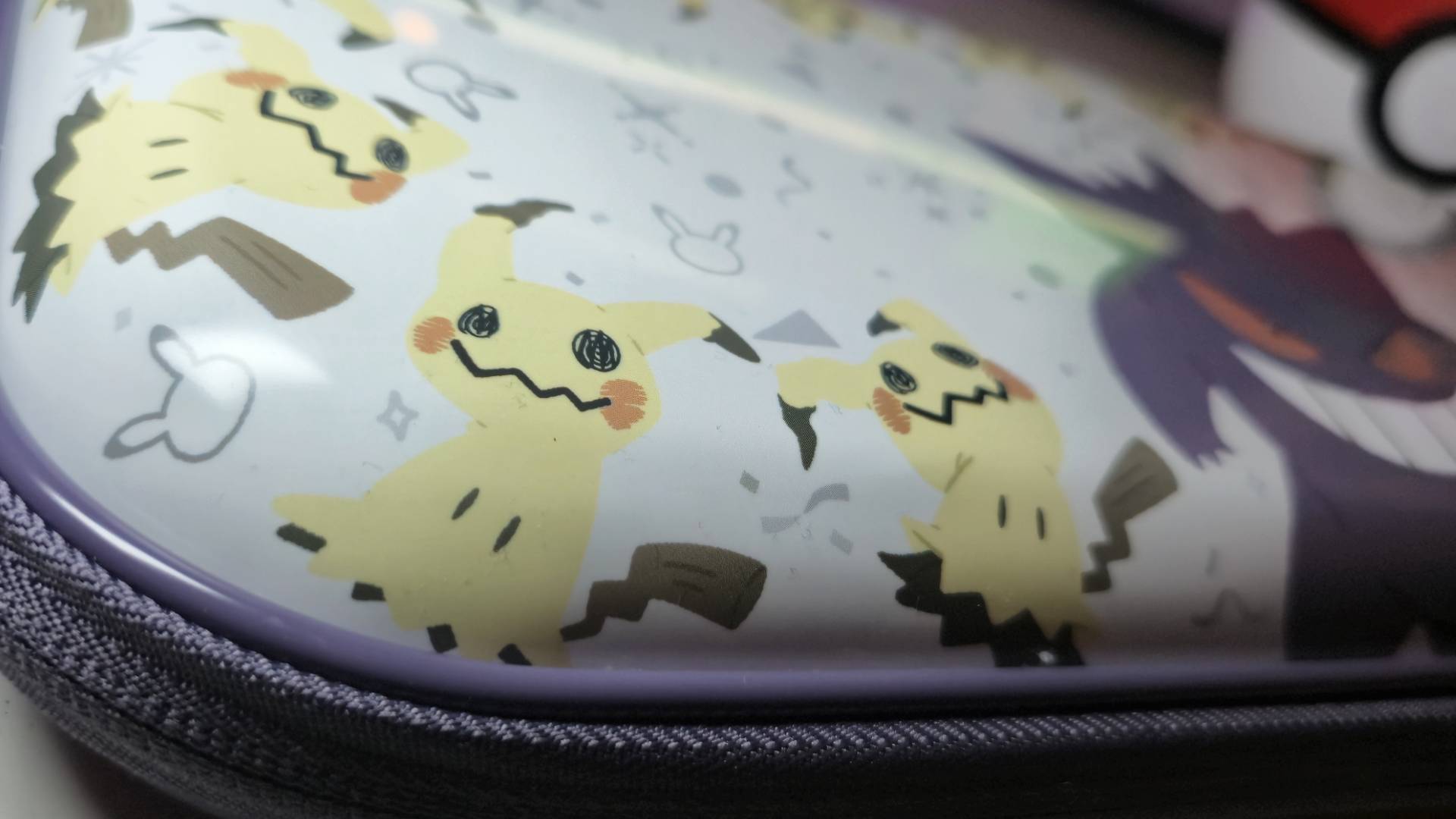Close up photo of the corner of a Hori Switch 2 showing showing a print of three Mimikyu Pokemon together.