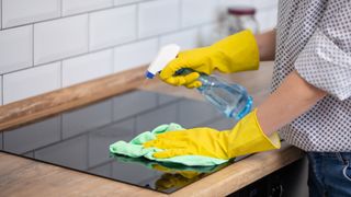 rubber glove hands showing how to clean a glass stovetop