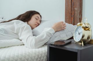 Woman asleep in bed next to alarm clock