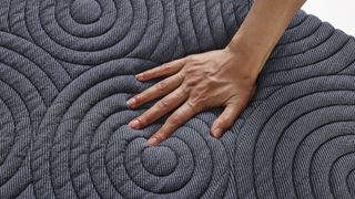 A hand pressing against the surface of the Ziwi ZiPP mattress, feeling the new foam support