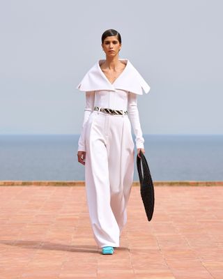 a Jacquemus model walks the fall/winter 2025 runway wearing an all-white look with a zebra-print belt