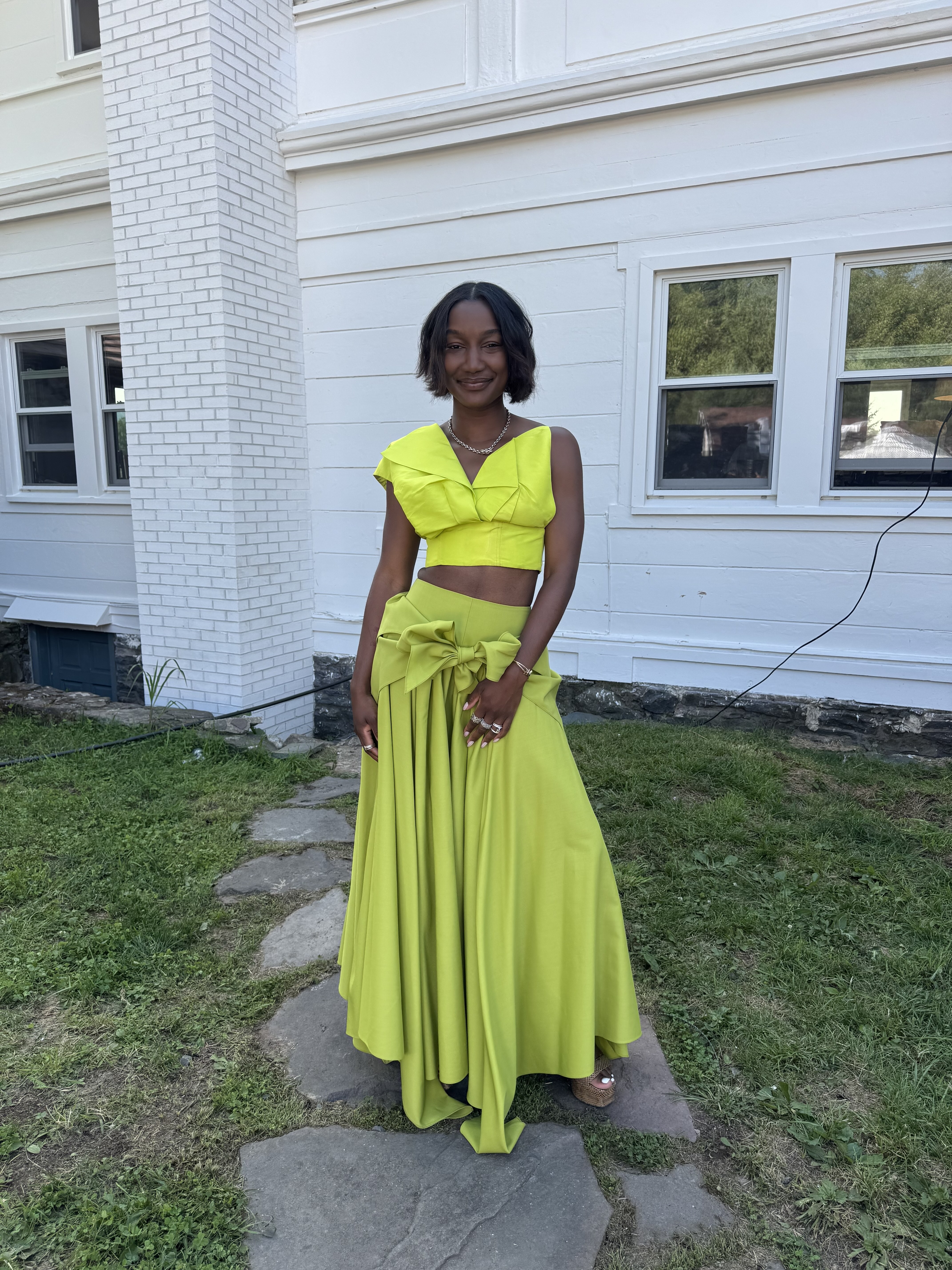 a woman wearing a bright yellow two-piece wedding guest dress, courtesy of Mecca James-Williams