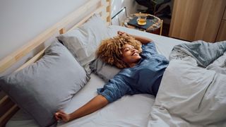Woman lying in bed with arms outstretched, waking up in the morning