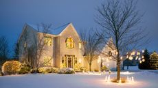 Christmas Decorated Home With Holiday Lighting in Winter with Front Yard Covered in Snow