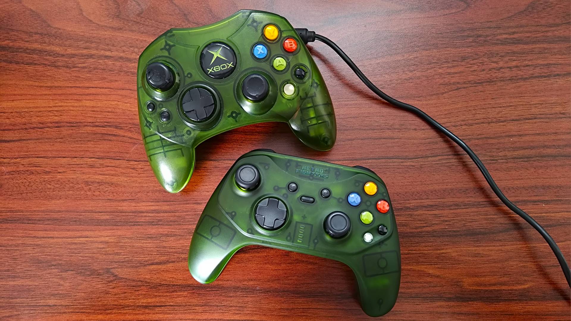 Retro Fighters Hunter sitting under OG Xbox S controller in transparent green sitting on woodgrain desk.