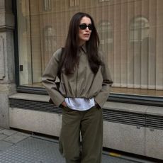 A woman walking on the street wearing an autumnal outfit with dark brown hair