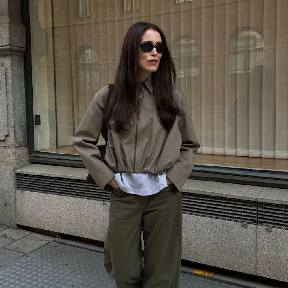 A woman walking on the street wearing an autumnal outfit with dark brown hair