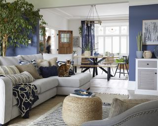 A relaxed blue nautical-themed open plan living room with L-shaped sofa and wooden bench