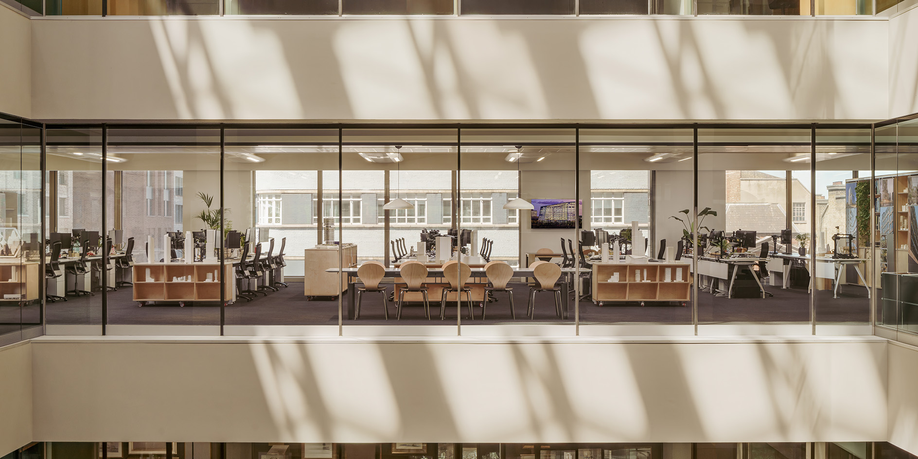 PLP Architecture&#039;s circular office design in neutral colours and soft light, showing empty workspace and timber seating and desks