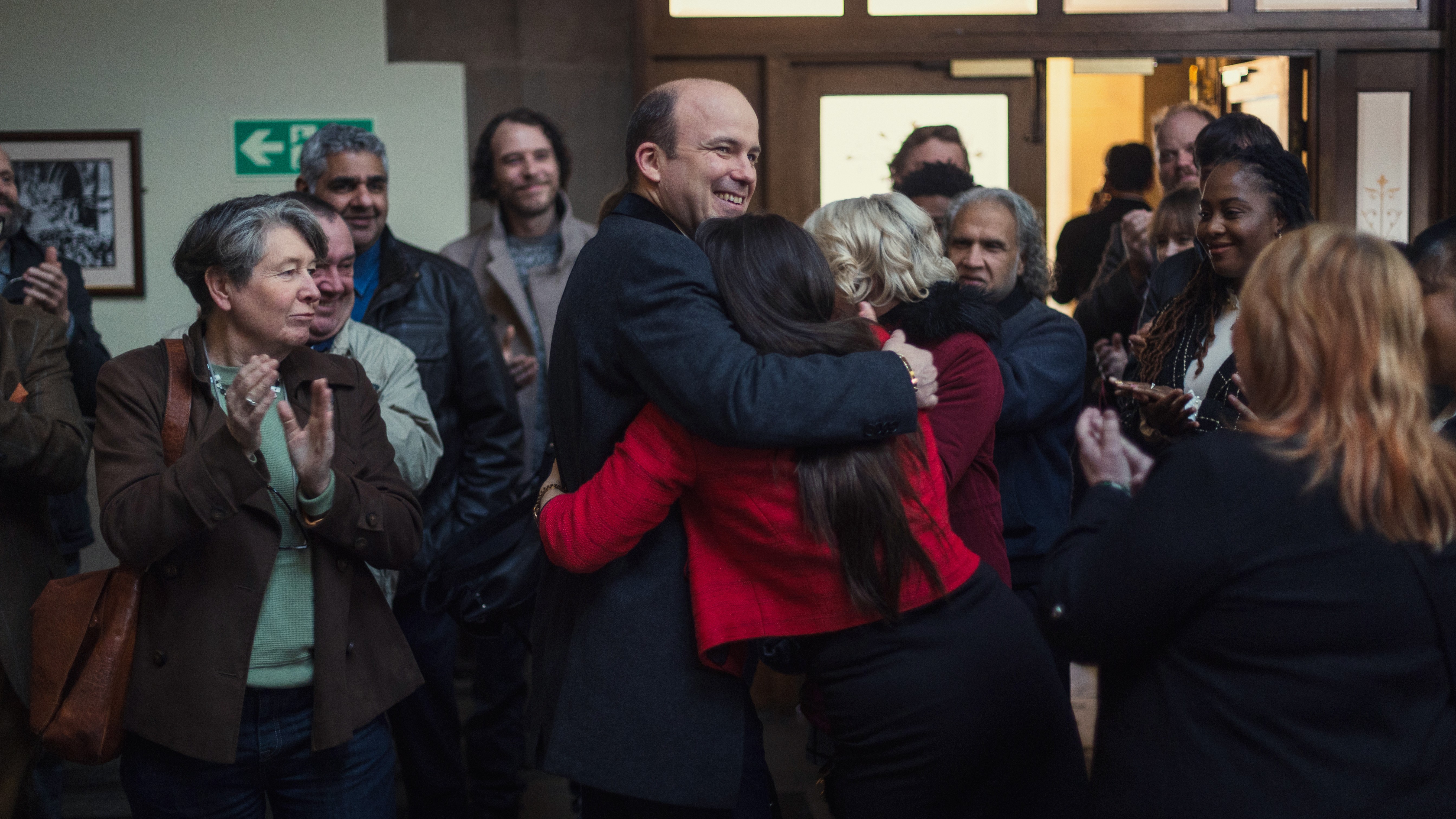 Dave Fishwick (Rory Kinnear) hugs his wife in among a crowd in a scene from Netflix's "Bank of Dave 2: The Loan Ranger"