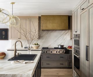 Pale wooden kitchen with marble island and gold range hood