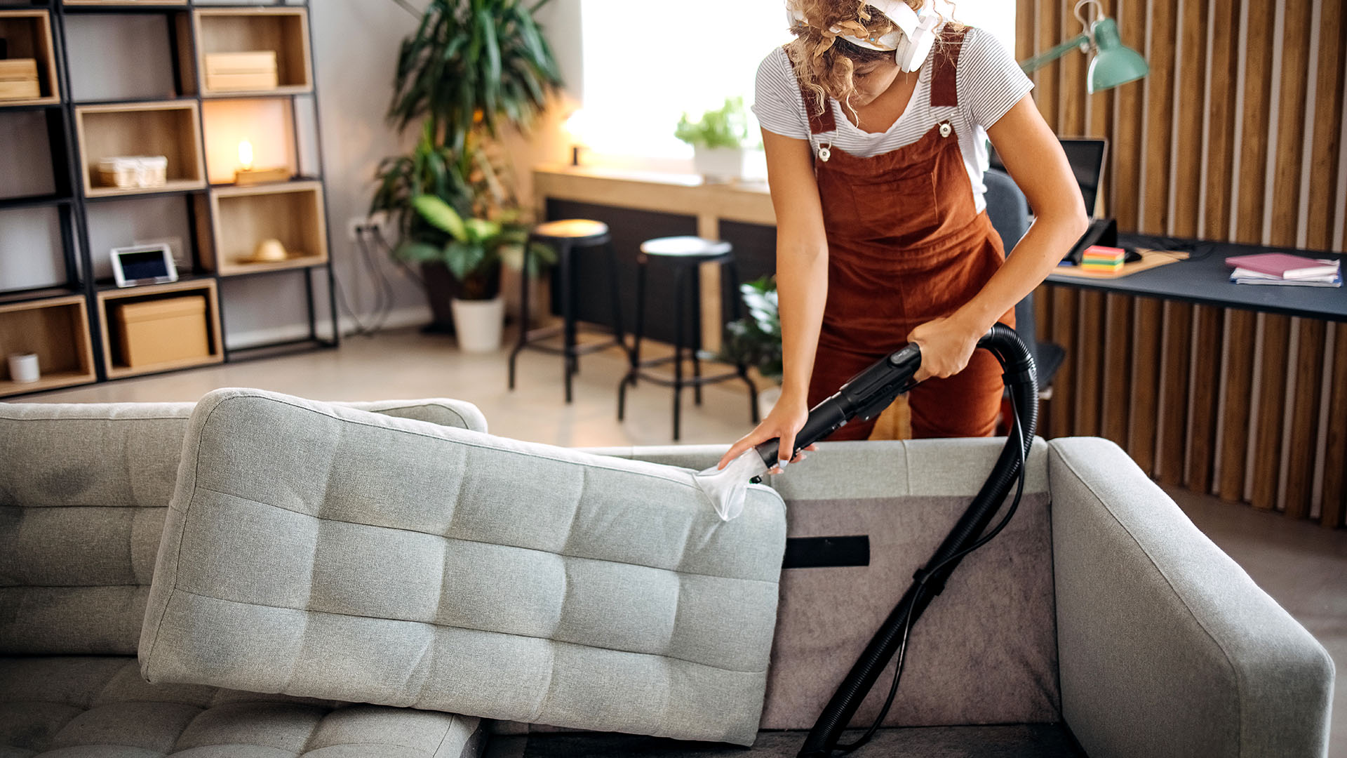 Woman vacuuming under her sofa cushions