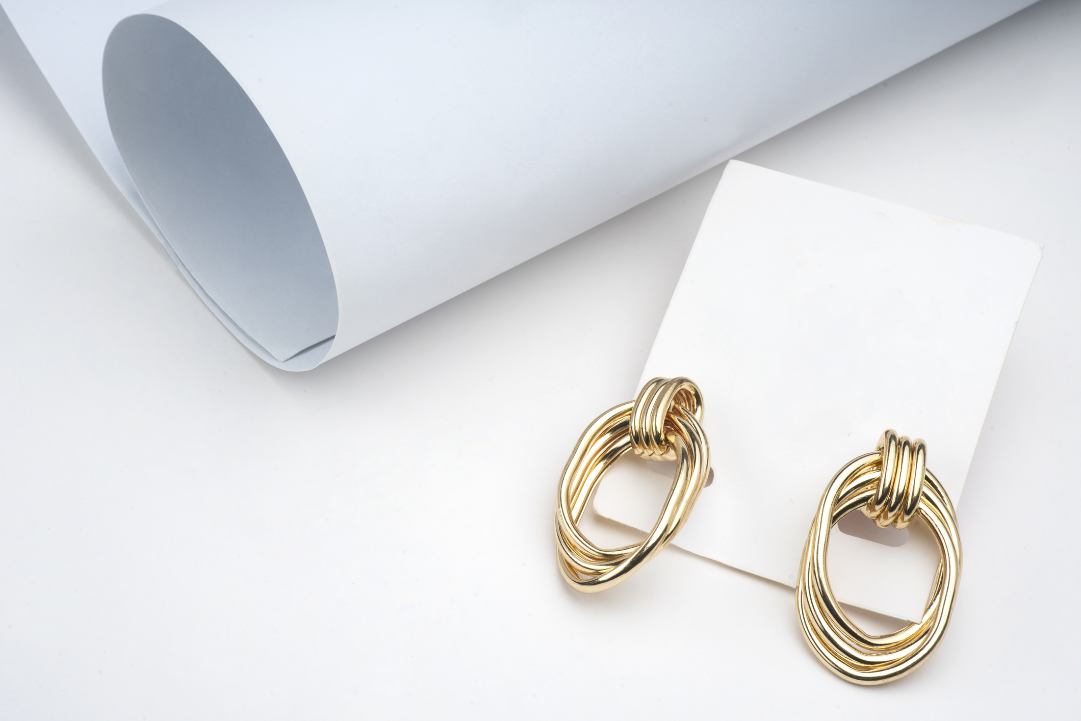 A pair of statement gold hoops on a white backdrop.
