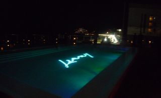 Rooftop pool at night, with "Lenny" lighting the surface of the water