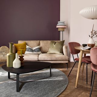 neutral living room with pink accents and rich plum painted feature wall behind brown sofa