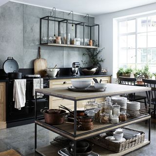 industrial black and wood open shelf kitchen island, matching shelves on wall, black oven and cooker in a large kitchen with grey flooring
