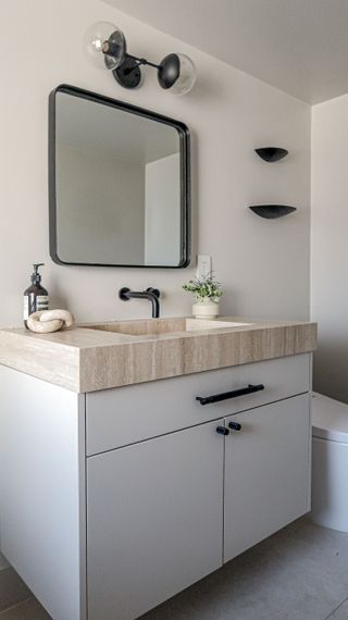 a white bathroom with a travertine countertop on the vanity