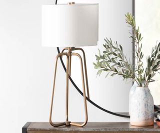 A tabletop lamp in bass and white on a sideboard