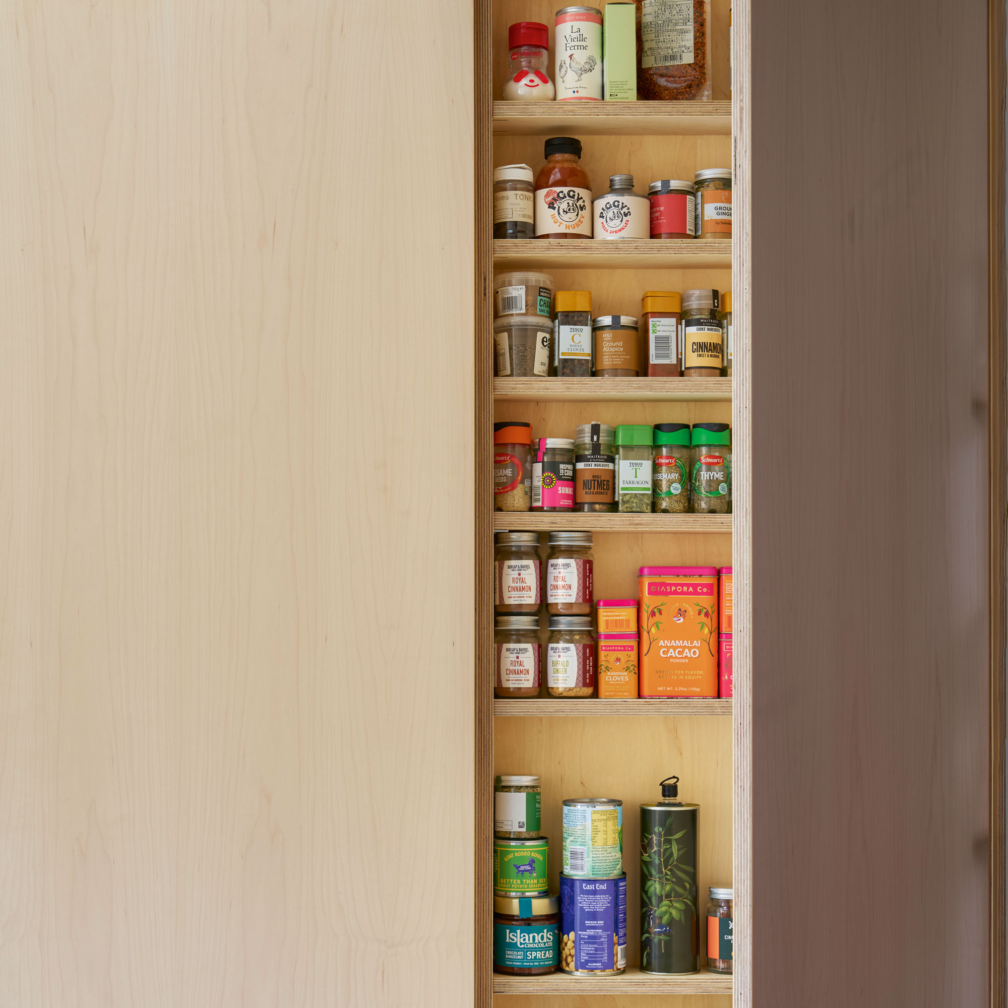 Wooden mini pantry holding spices and oils.