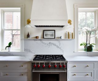 A white and marble kitchen with a plastered range hood