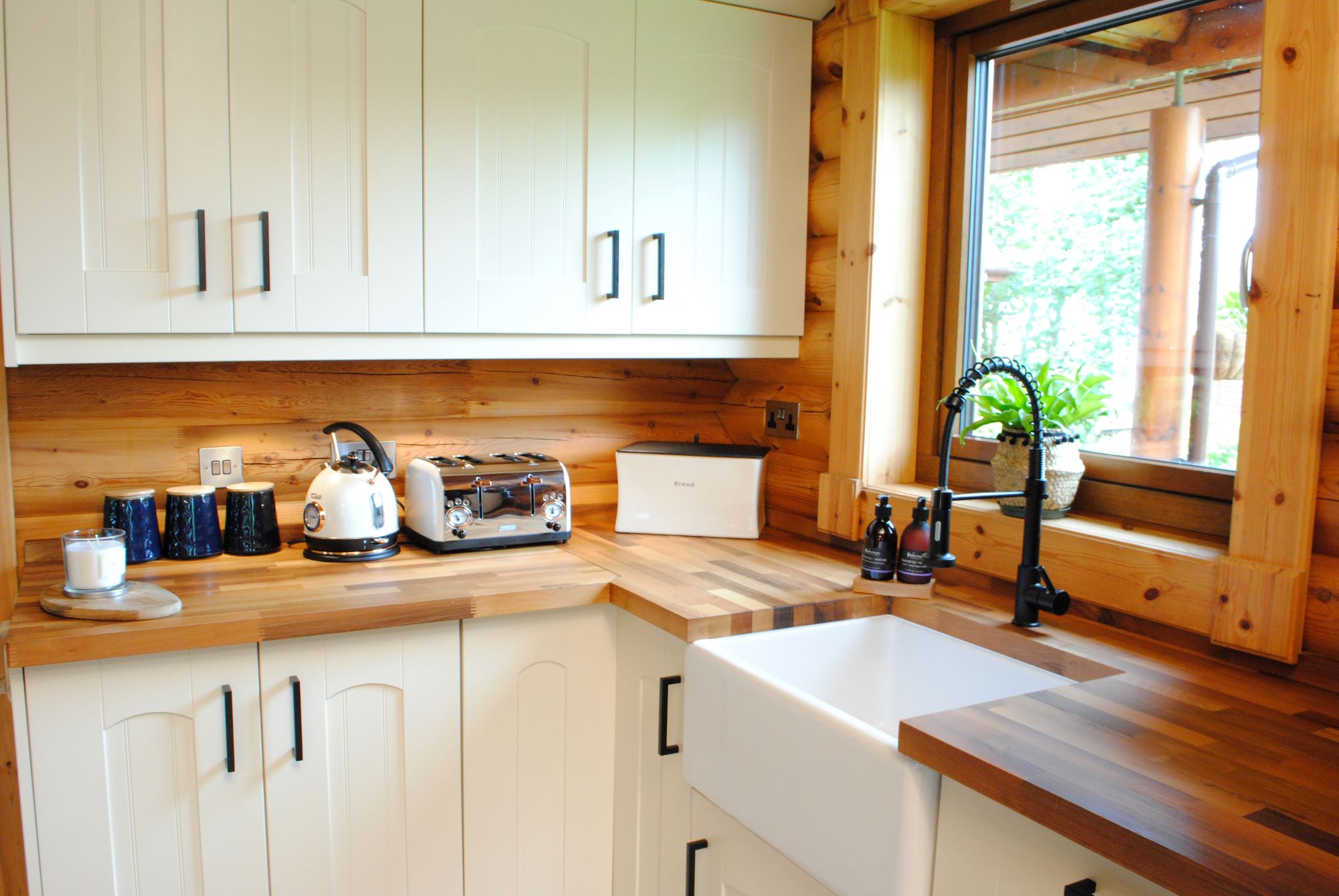 The kitchen has wooden worktops and white wooden cabinets plus a wooden window looks out onto the garden over the sink