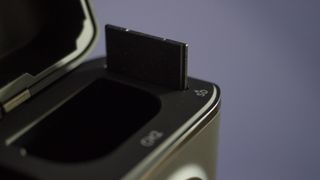 The Llano Dual Camera Battery and Charger set on a wooden surface against a purple background