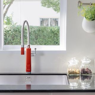 kitchen with white wall and black countertop with red smeg tap and wash basin