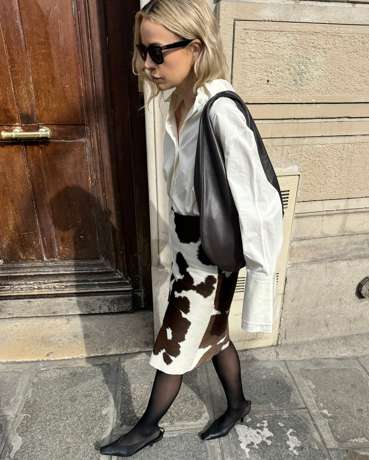 @stephaniebroek wearing a white button-down shirt with a cow-print skirt an tights.