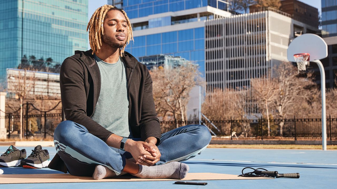 Person meditating on a baseball court wearing the Fitbit Charge 5 fitness tracker