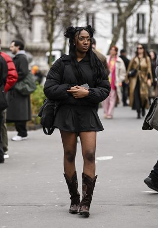 woman wearing black jacket, black skirt and cowboy boots