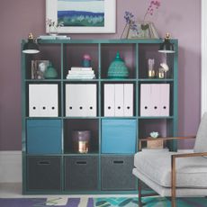 A teal-painted IKEA KALLAX storage unit against a purple wall