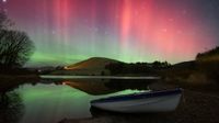 a red and green aurora over a scenic lake