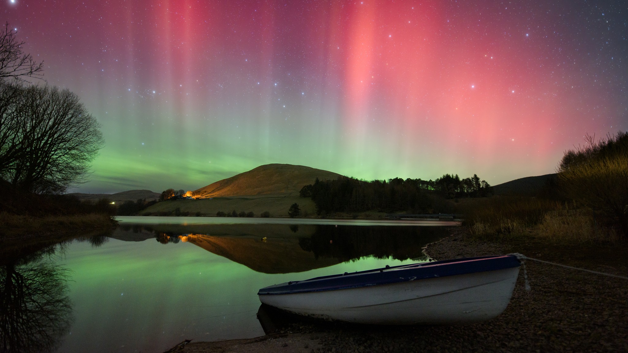 a red and green aurora over a scenic lake
