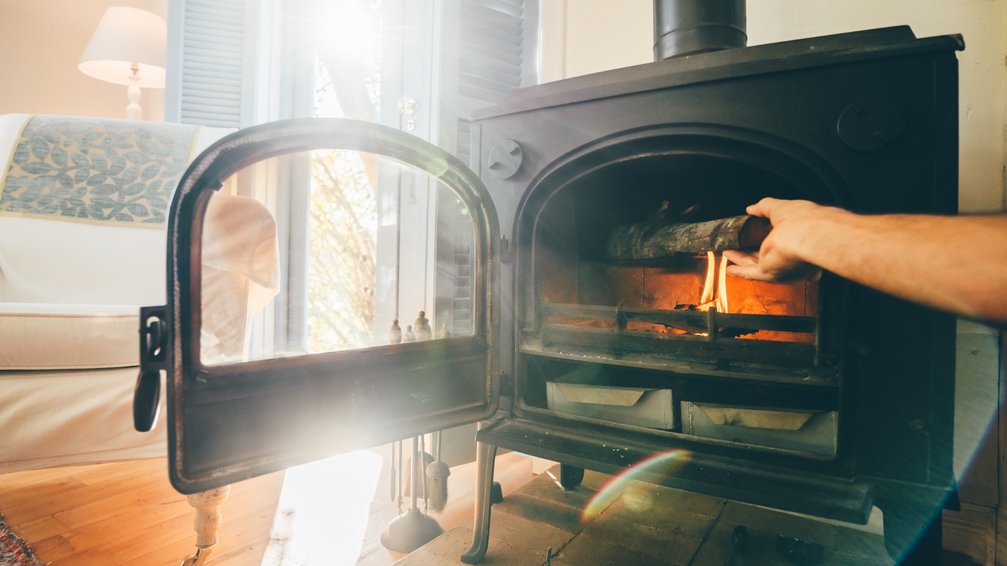 Hand adding wood to a log burning stove