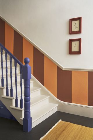 hallway with staircase, spindles and handrail in blue and panelling in orange and red vertical blocks