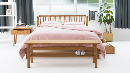 A wooden bed with a pink duvet cover in a light-filled bedroom