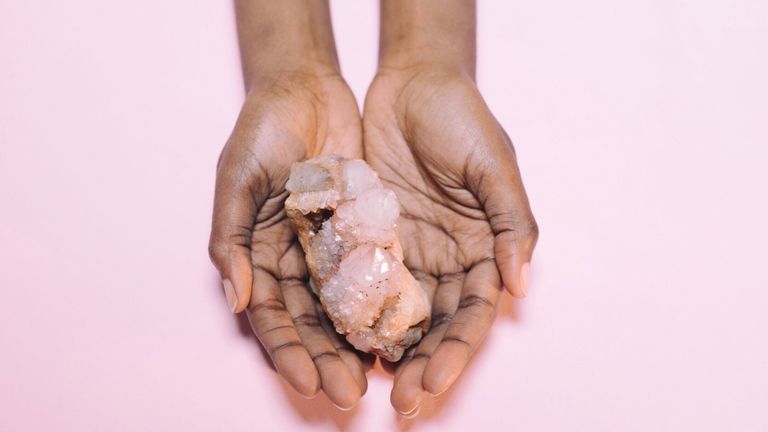 Close-Up Of Hand Holding Crystal Over White Background