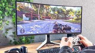 Alienware 34 Curved QD-OLED Gaming Monitor on a desk showing a game being played