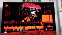 Switch Virtual Boy on woodgrain table with TV in backdrop and Virtual Boy Wario Land on screen.