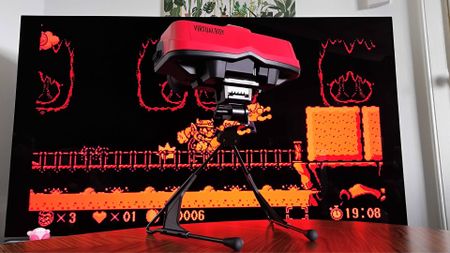 Switch Virtual Boy on woodgrain table with TV in backdrop and Virtual Boy Wario Land on screen.