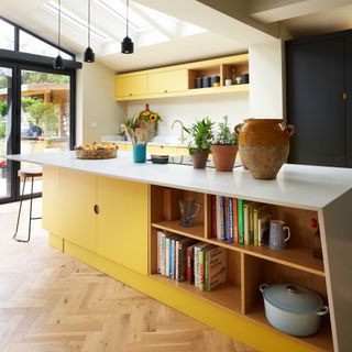 modern yellow and navy blue kitchen with kitchen island, bar stools and three sky lights and patio doors