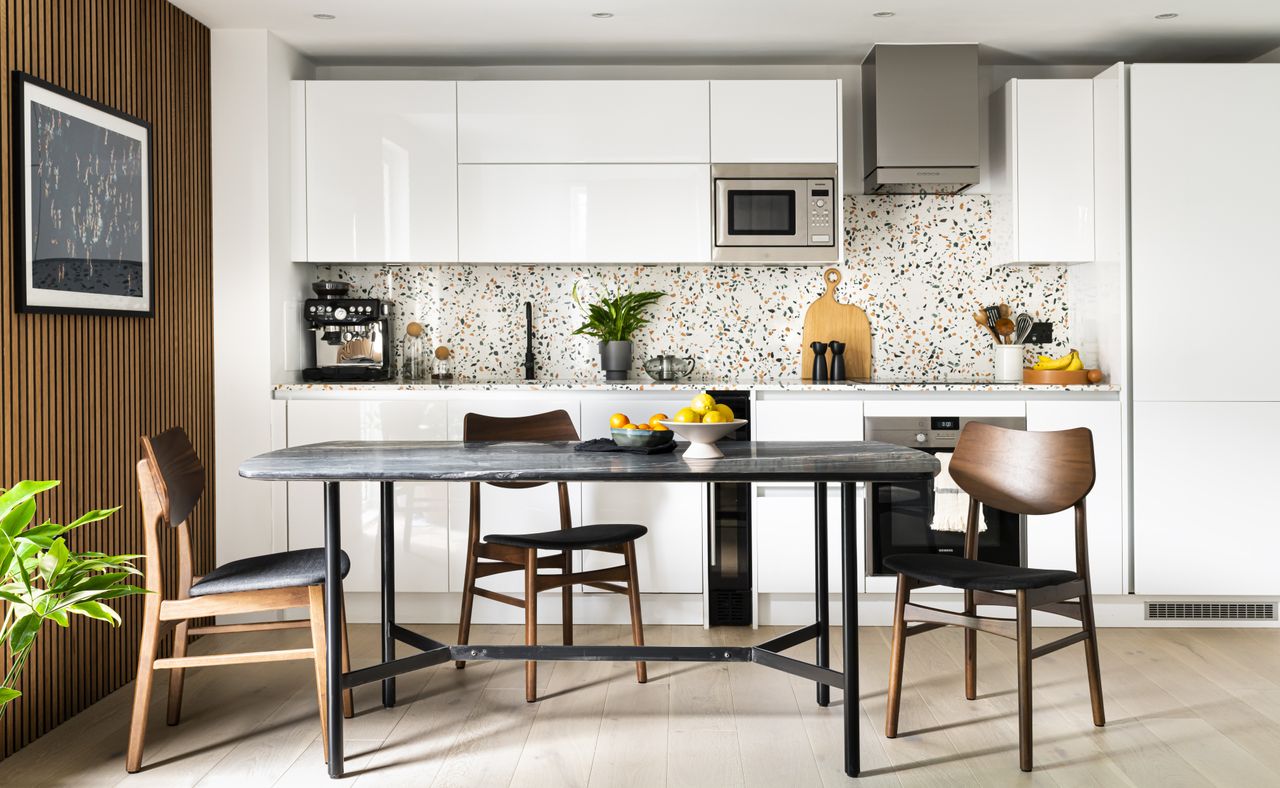 Kitchen with white units and dining table