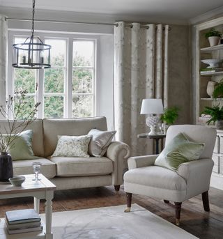 Gray living room with two seater sofa and chair, chandelier and pineapple table lamp