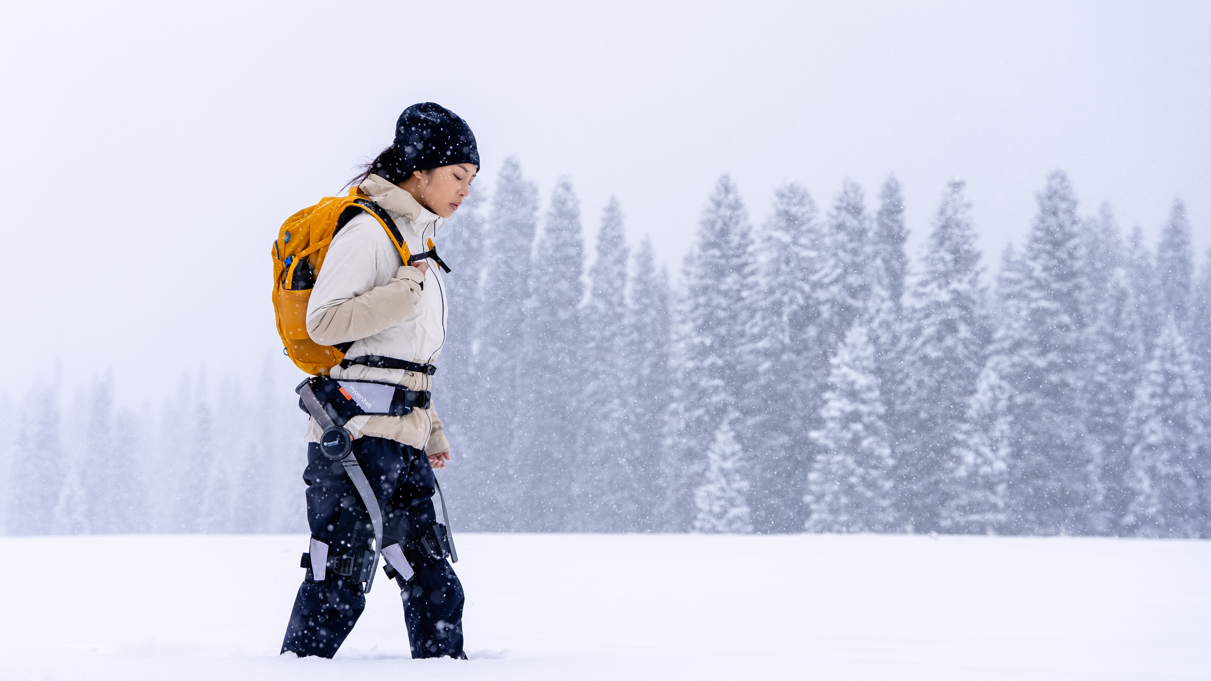 A woman hiking in the snow wearing the Hypershell X Exoskeleton