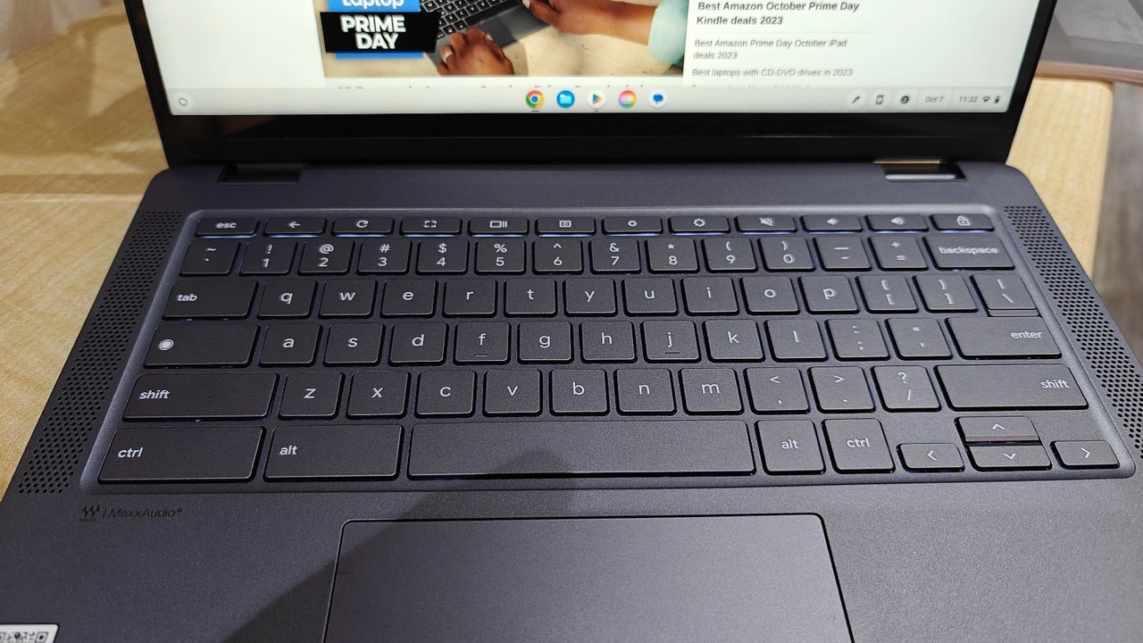 Close up shot of a laptop keyboard, sitting open on a wooden desk.