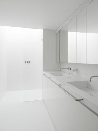 White bathroom with a white sink and mirrors