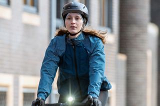 A women cycles towards the camera wearing Altura NightVision Storm rain jacket