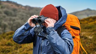 Survival skills and gadgets 101: a man uses a pair of binoculars to aid his navigation on Dartmoor