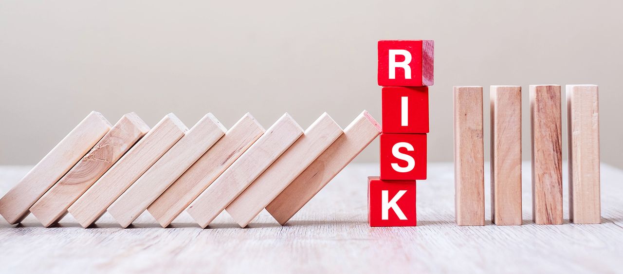 wooden blocks leaning against red letter blocks spelling &quot;risk&quot;