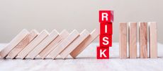 wooden blocks leaning against red letter blocks spelling "risk"